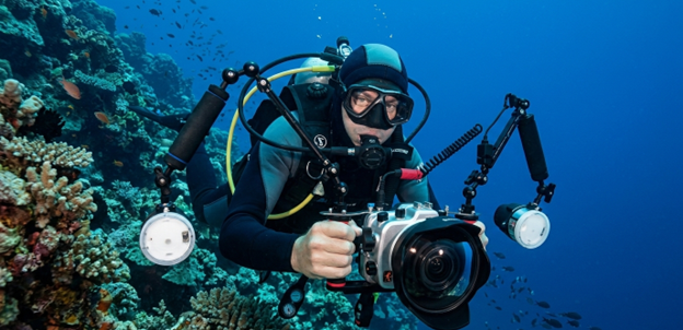 Scuba diver using professional underwater camera with strobes and housing